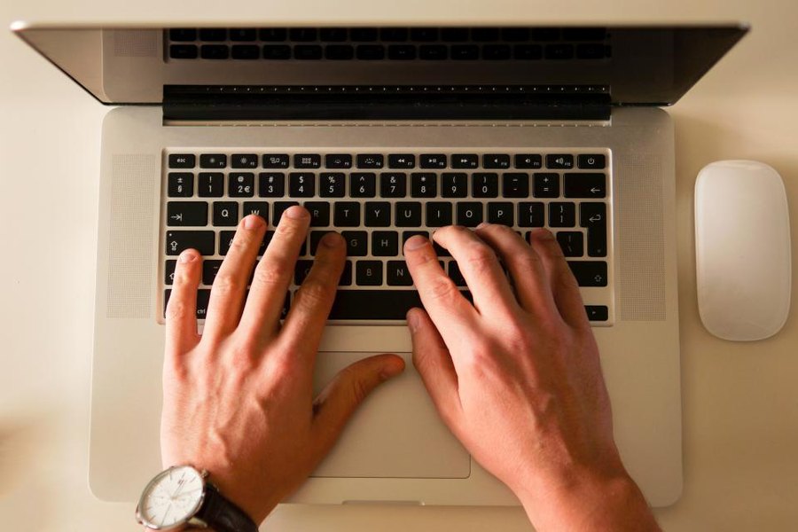 ノートパソコンのキーボードを打つ両手